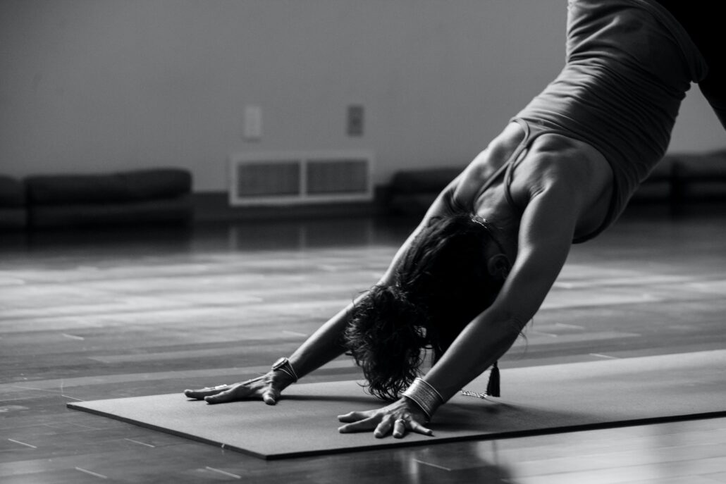 Black and white image of a woman in downward facing dog.